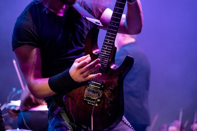 Musician shredding on guitar while drummer plays in the background