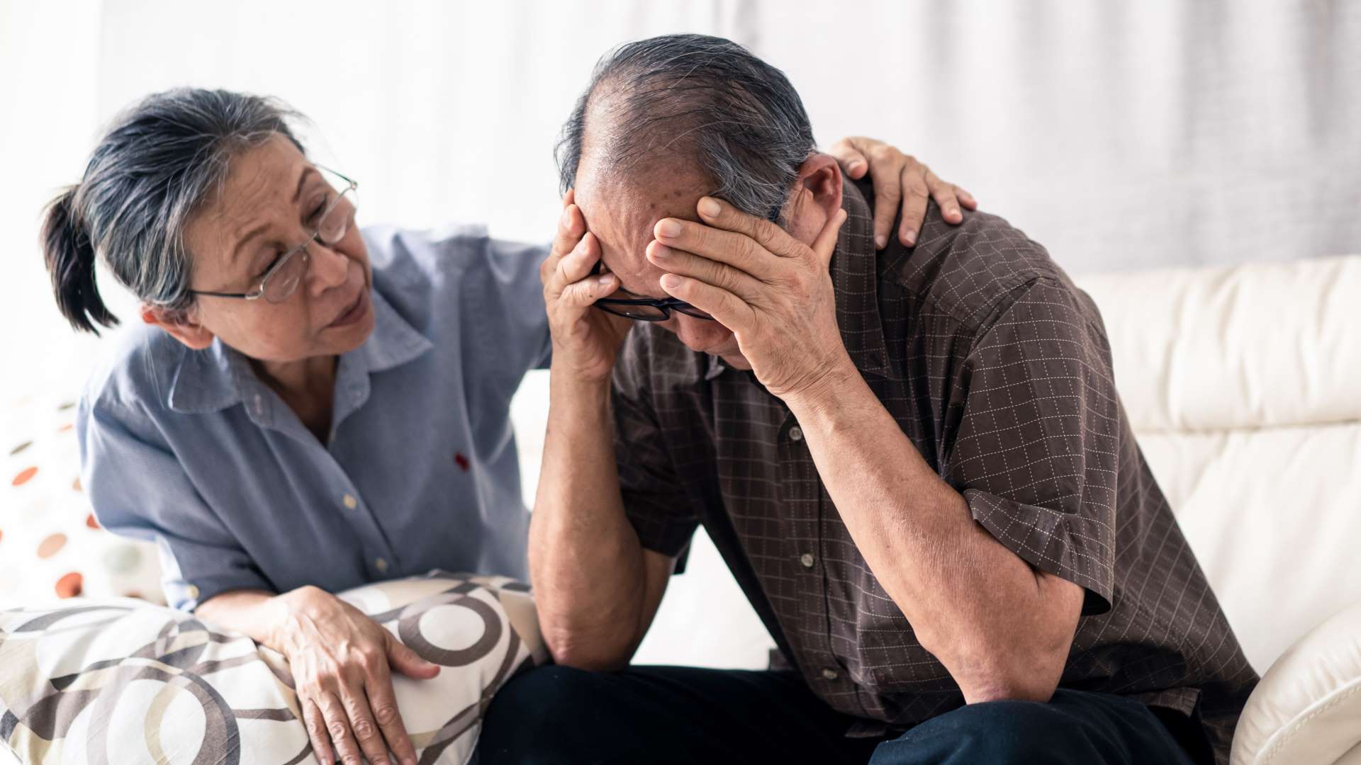 elderly man being consoled by wife
