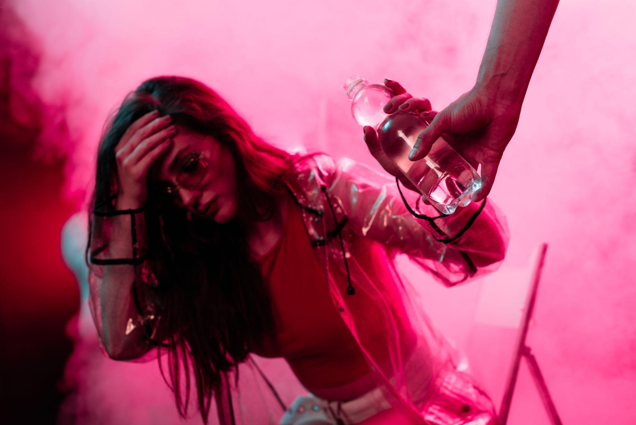 sick girl headache taking bottle of water in nightclub