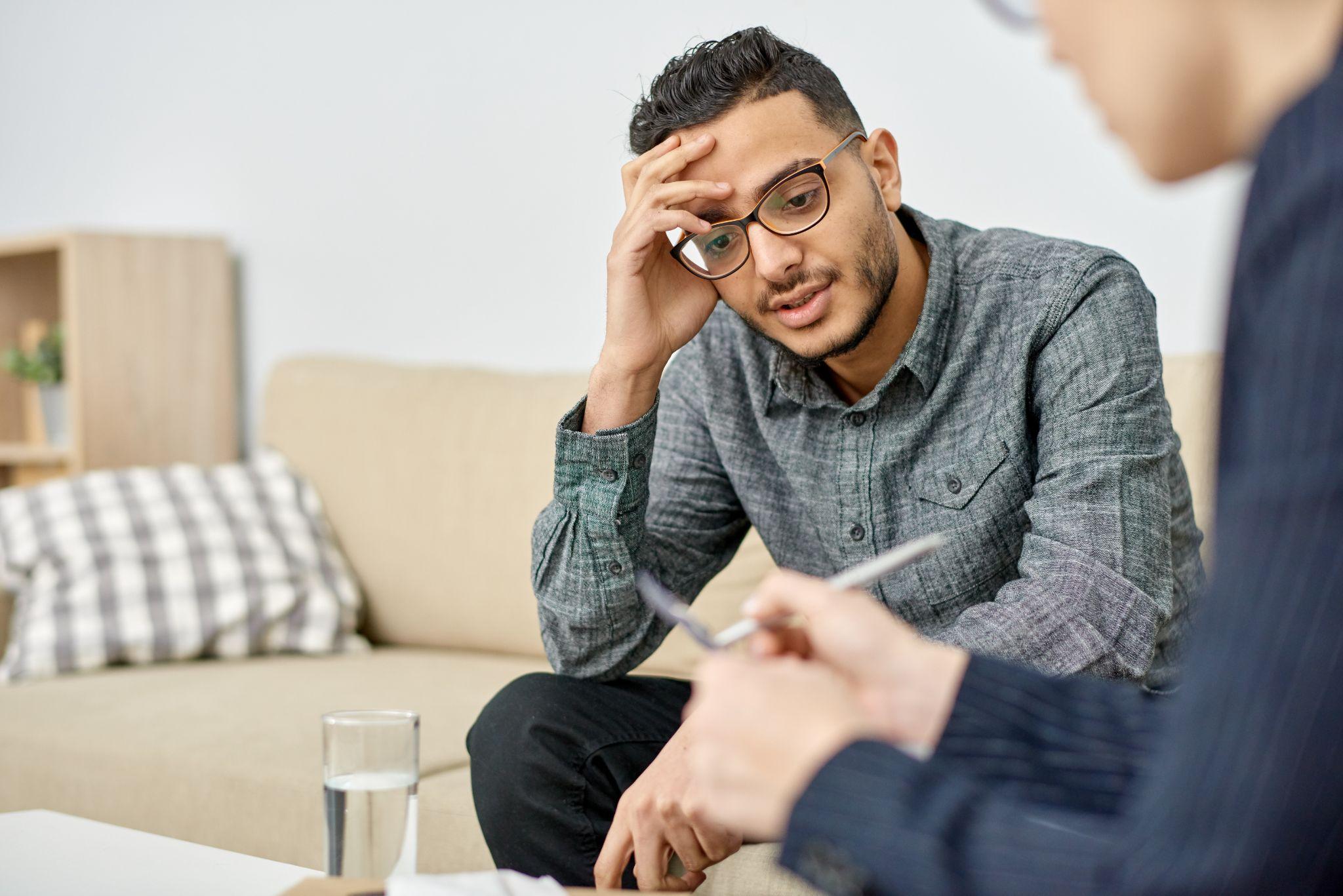 psychologist taking notes on clipboard while consulting depressed patient during therapy session