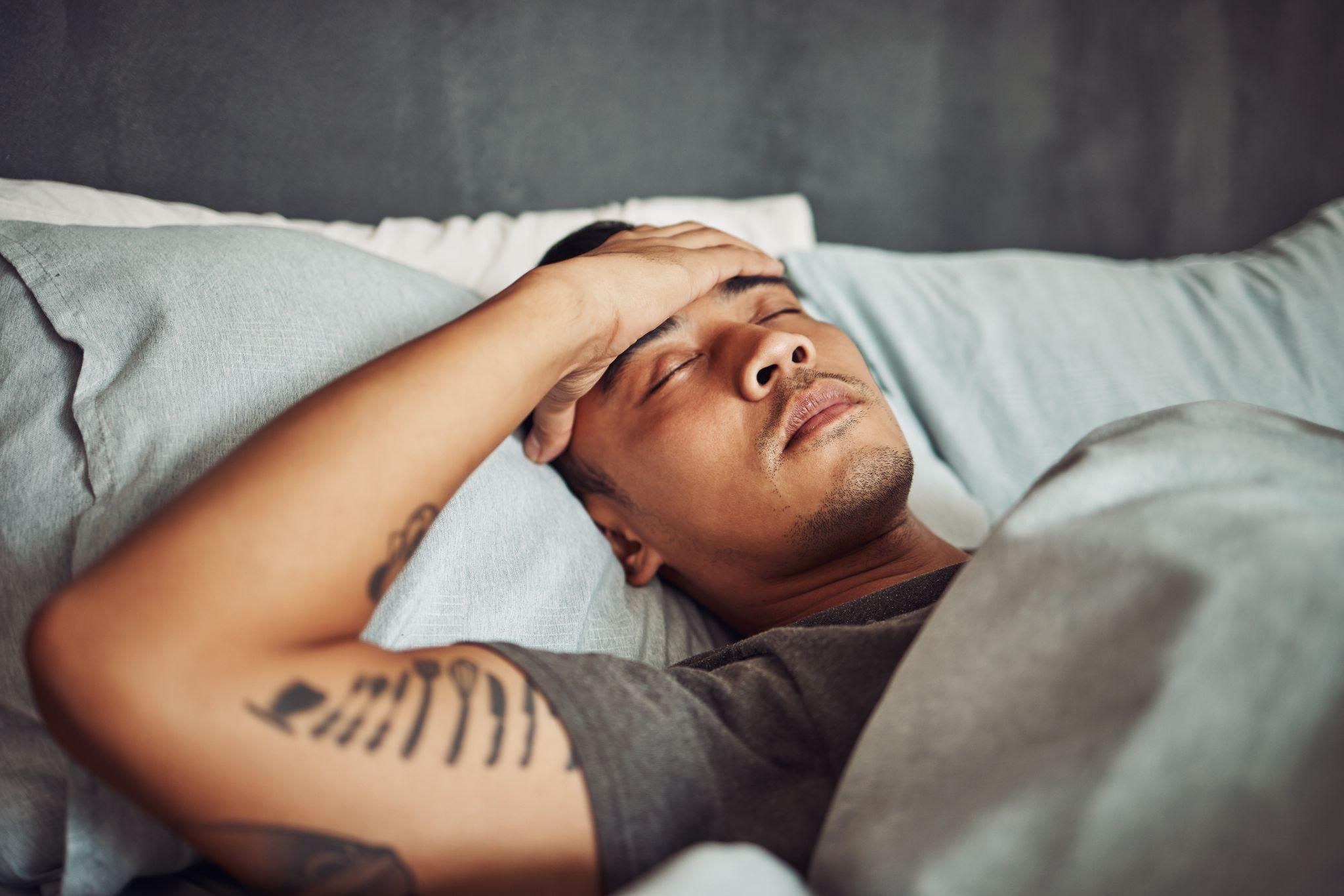 Tired, rest and sick man sleeping in the bedroom while in recovery