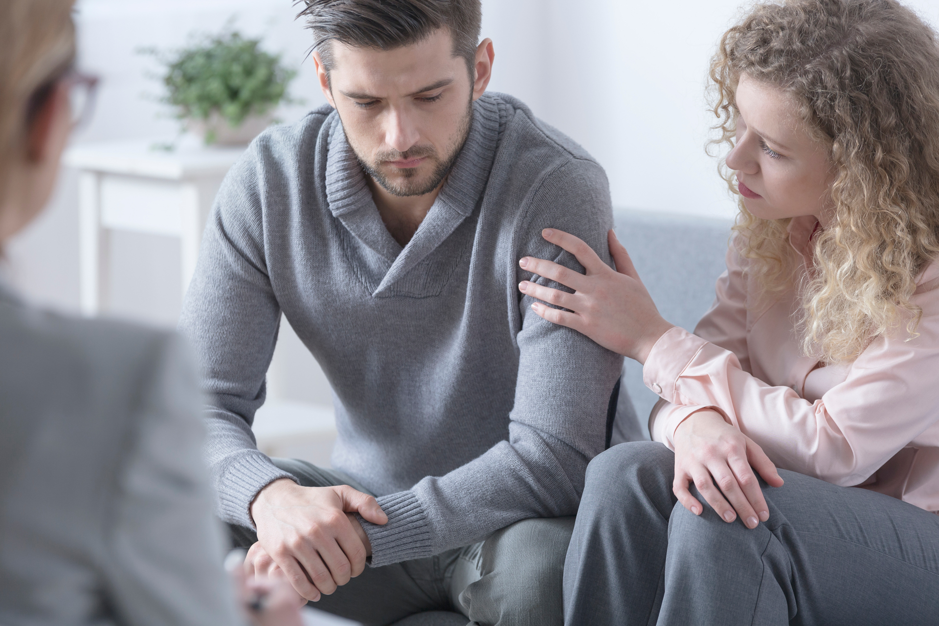 Woman reassuring man when discussing family roles in addiction during therapy