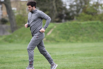 Man running in grey fitted jogging suit