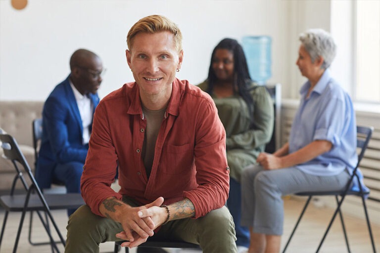 Happy man looking out from addiction recovery support group