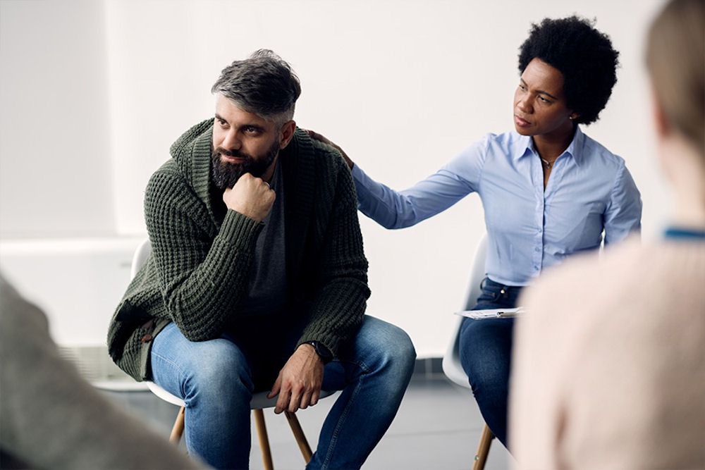 Group therapy reassuring man opening up about unhealthy coping mechanisms