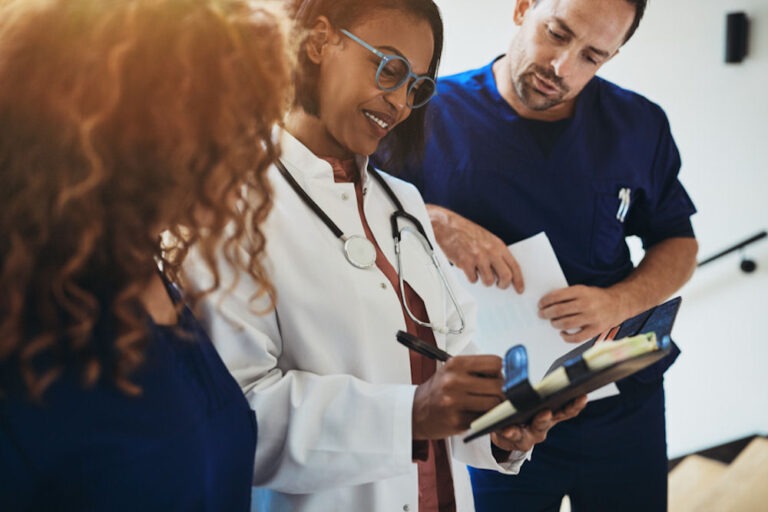 Doctor and two nurses looking down at clipboard with treatment plan for late-stage alcoholism