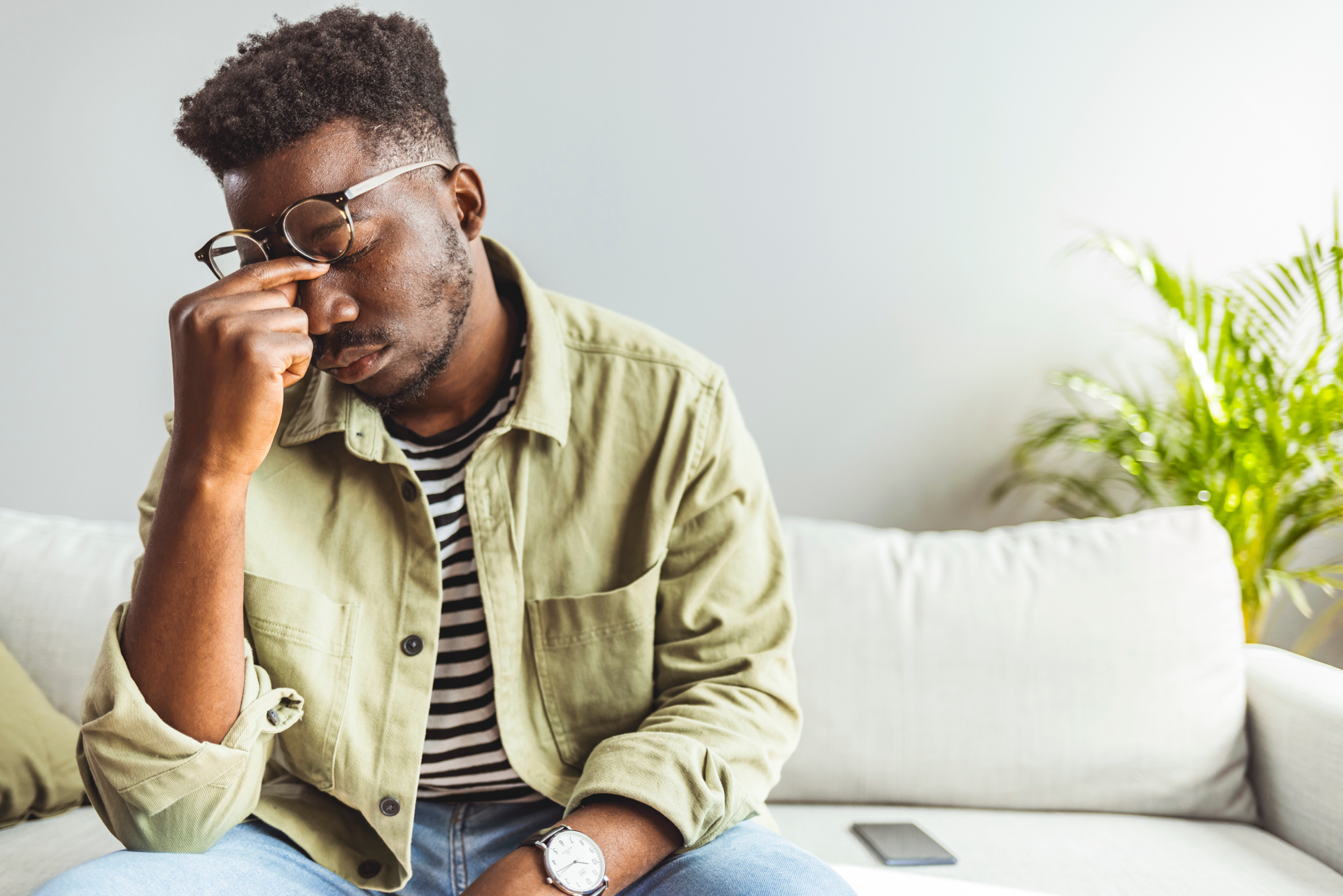 Frustrated young man pinches sinuses under glasses